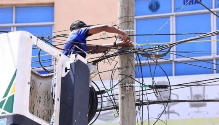 Field technician working on aerial fibre connections on a utility pole