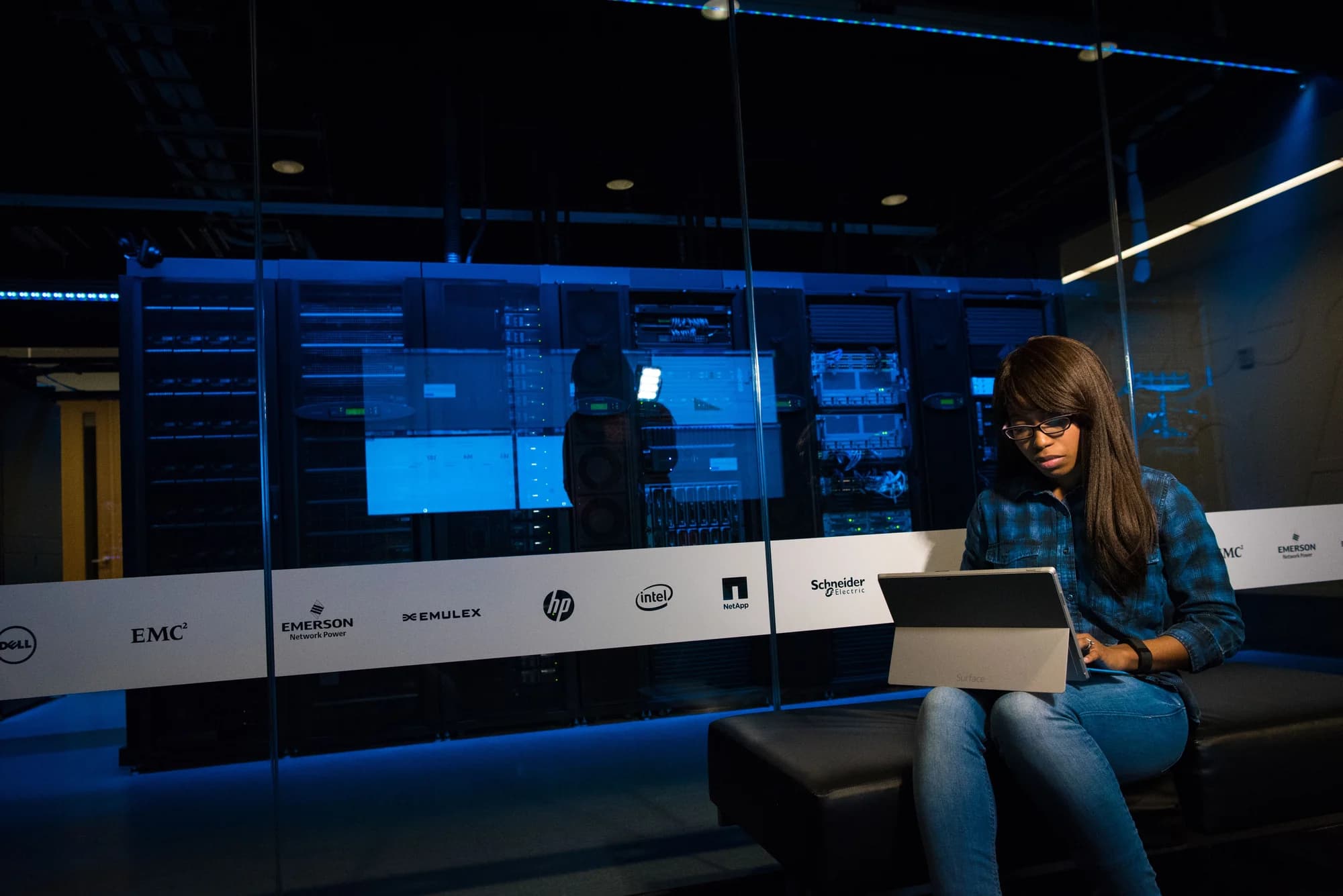 An engineer working on a laptop beside server racks