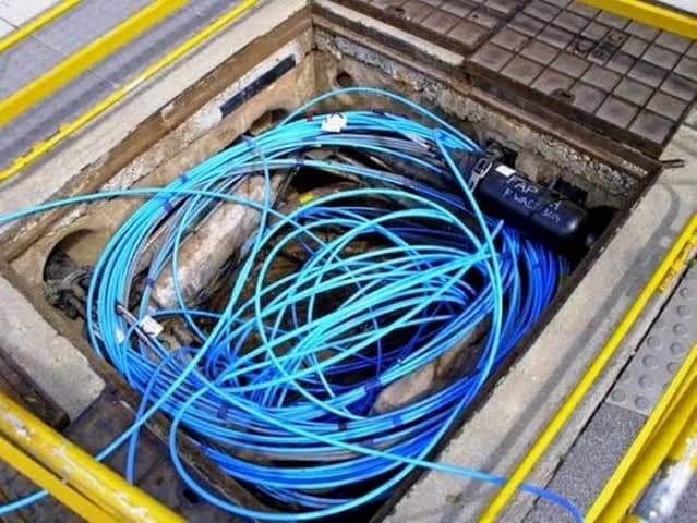 Blue fibre optic cables coiled inside an underground handhole