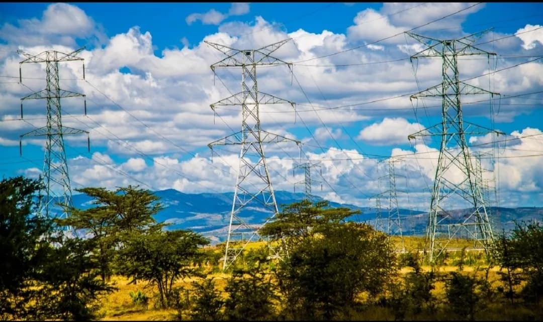 High-voltage transmission towers crossing Kenyan rangeland toward distant mountains