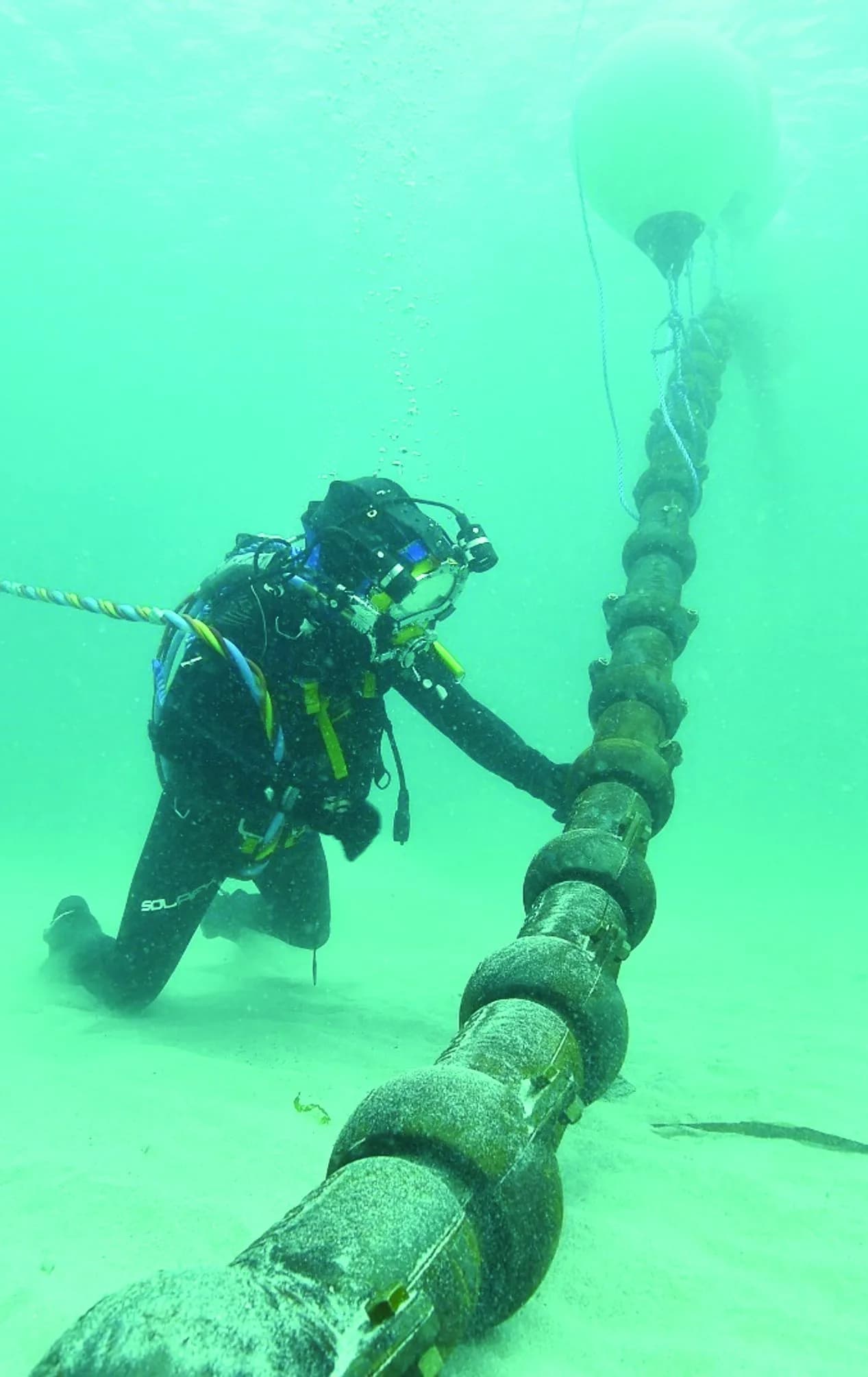 Diver inspecting a submarine cable on the seabed