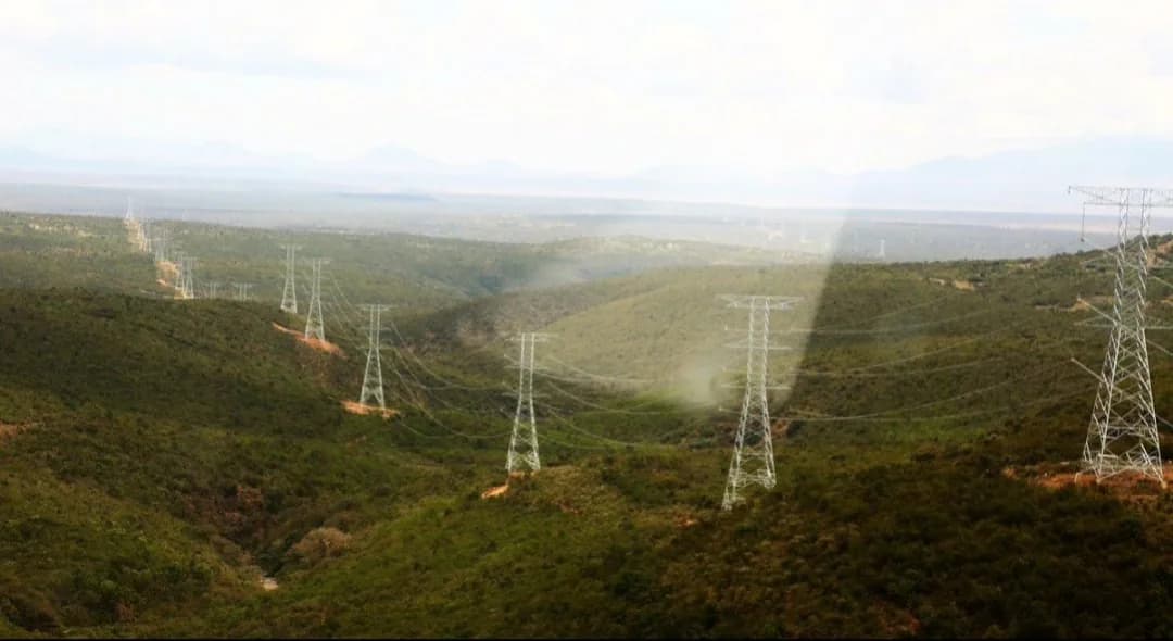 A corridor of high-voltage transmission towers running through hills toward the Ethiopian border