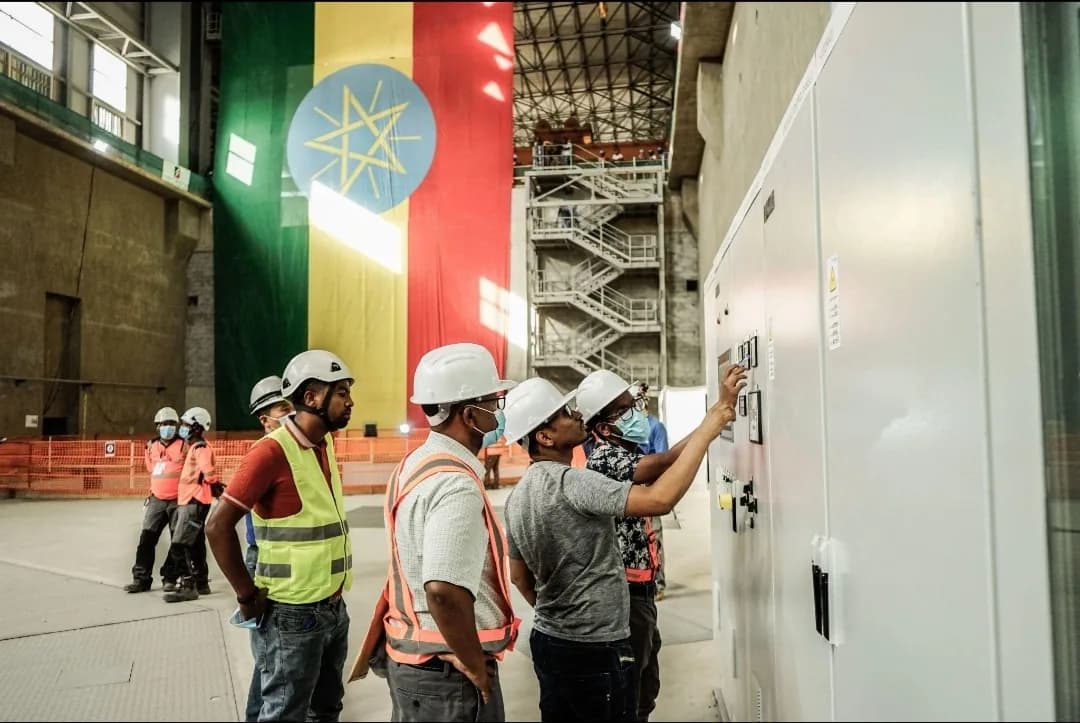 Engineers operating switchgear inside the GERD powerhouse beneath a large Ethiopian flag